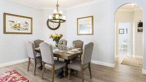 A dining room with a wooden table, six chairs, a chandelier, and two framed pictures on the walls. - MARCH LAST MINUTE AVAILABLE! (Davenport)