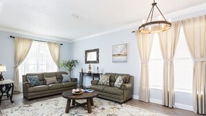 A living room with two sofas, a coffee table, a lamp, and a large window with curtains. - MARCH LAST MINUTE AVAILABLE! (Davenport)