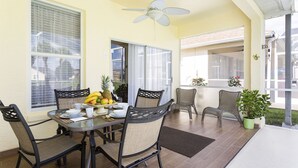 A dining area with a table set for four, surrounded by wicker chairs, a ceiling fan, and a view of the street. - MARCH LAST MINUTE AVAILABLE! (Davenport)