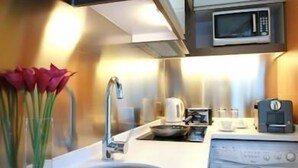 A compact kitchen with a sink, microwave, and washing machine. - Knight On Wyndham (Hong Kong)