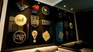 A wall with various logos and signs, including 'FIRST', '1070', 'KNT', 'HDP', and 'SEAL'. - Knight On Wyndham (Hong Kong)