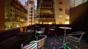 A rooftop terrace with outdoor seating and a cityscape view. - Knight On Wyndham (Hong Kong)