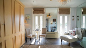 Una habitación luminosa con un armario grande de madera, una mesa de comedor con sillas, un sofá y una lámpara de araña.