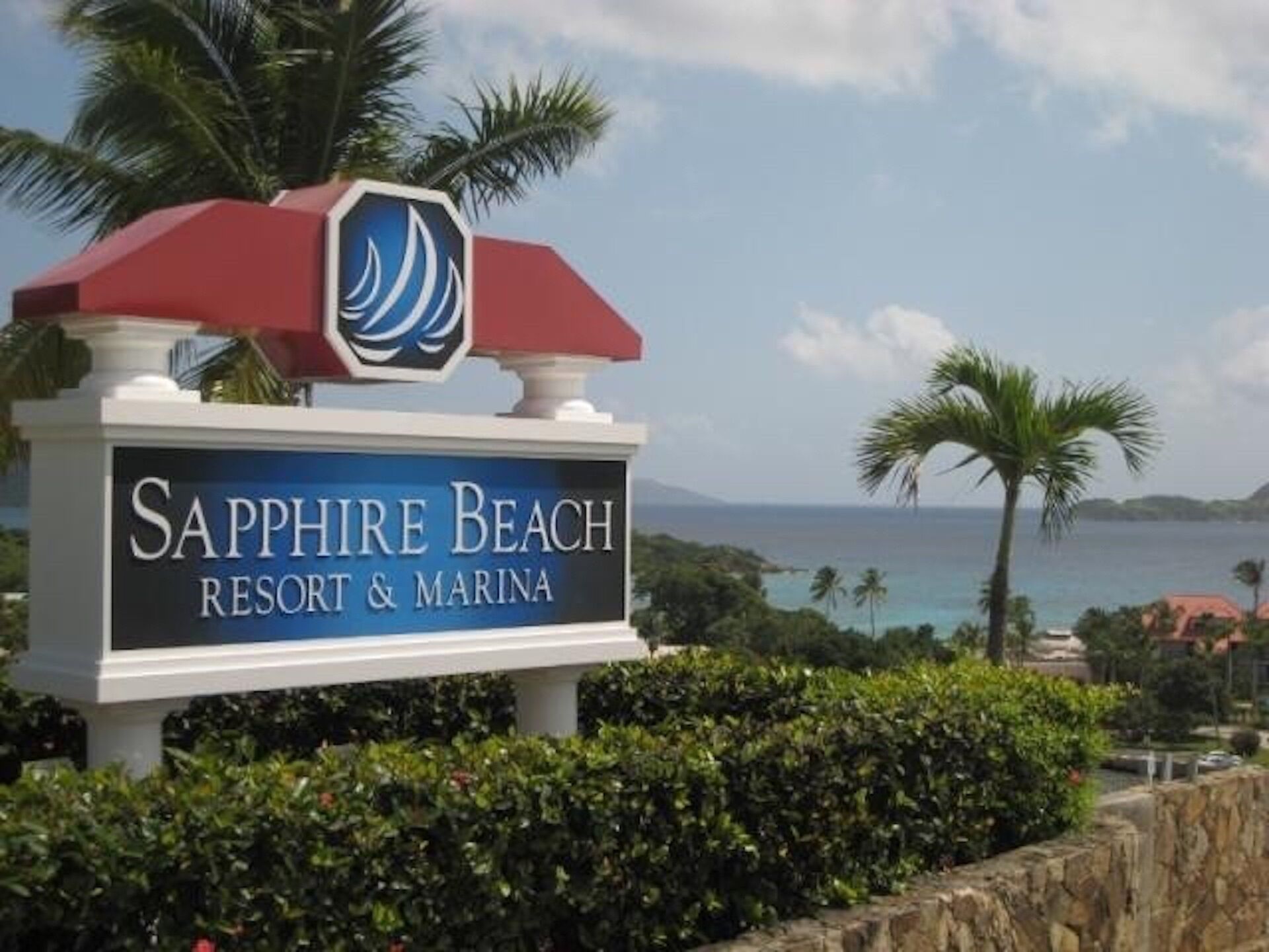 Señal del Sapphire Beach Resort & Marina, con vista al océano y palmeras al fondo.