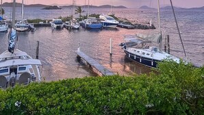 Ein Yachthafen mit mehreren Segelbooten, ruhigem Wasser und weiter Sicht auf Land.