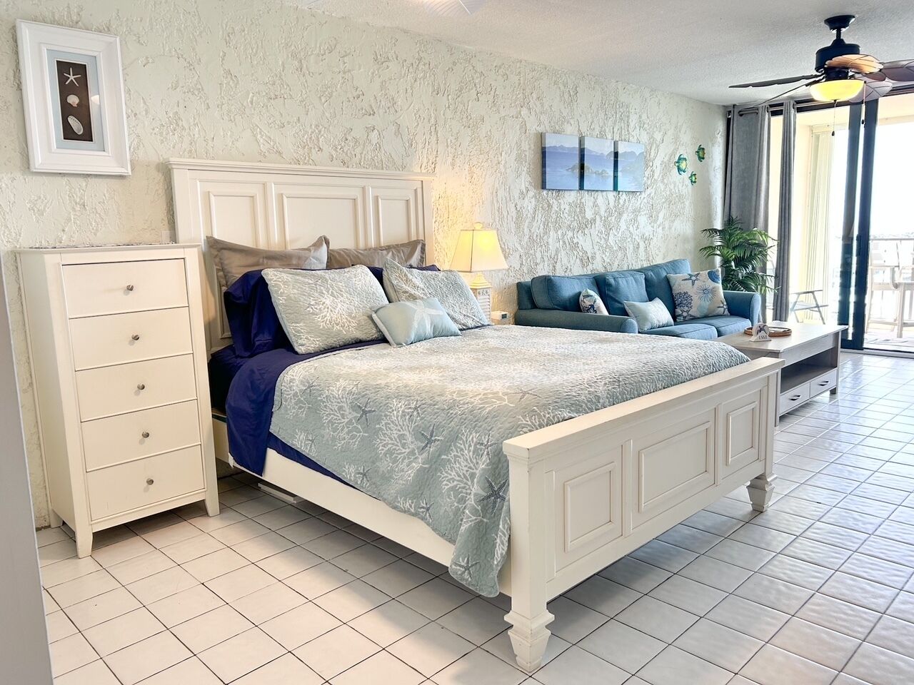 Quarto com cama, penteadeira e vista para o exterior.