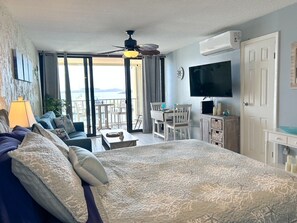 Camera da letto con un letto grande, una scrivania, una sedia, una televisione e un balcone con vista.