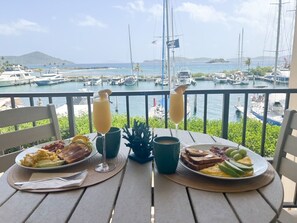 Una tavola imbandita con piatti per la colazione, due bicchieri di succo d'arancia e una pianta tropicale.