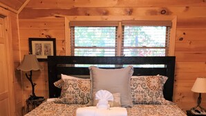 A wooden cabin bedroom with a bed, two bedside lamps, and a window with blinds. - Long Range Views! 3 Fireplaces-Sleeps 20-Blue Ridge-Pool Table/HotTub-Pets OK. (Blue Ridge)