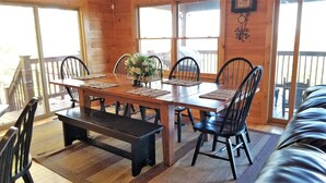 A wooden dining table with four chairs, a bench, and a vase with flowers. - Long Range Views! 3 Fireplaces-Sleeps 20-Blue Ridge-Pool Table/HotTub-Pets OK. (Blue Ridge)