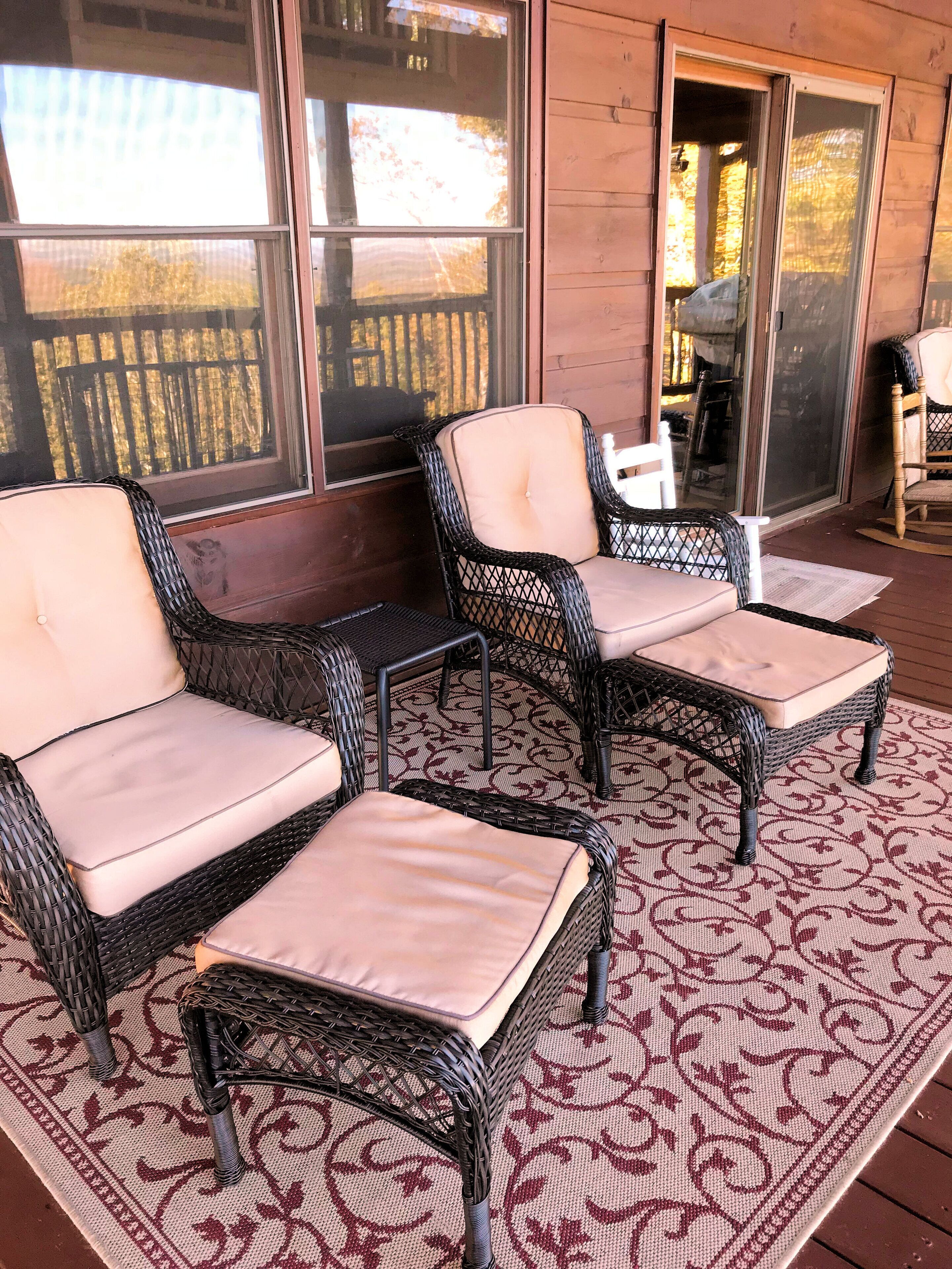 Un espacio de descanso techado al aire libre con muebles de mimbre y un tapiz estampado.