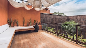 A balcony with a wooden floor, a white sofa, a large black vase, and a wooden fence. - Sana Vie Villa Seminyak by Ini Vie Hospitality (Seminyak)