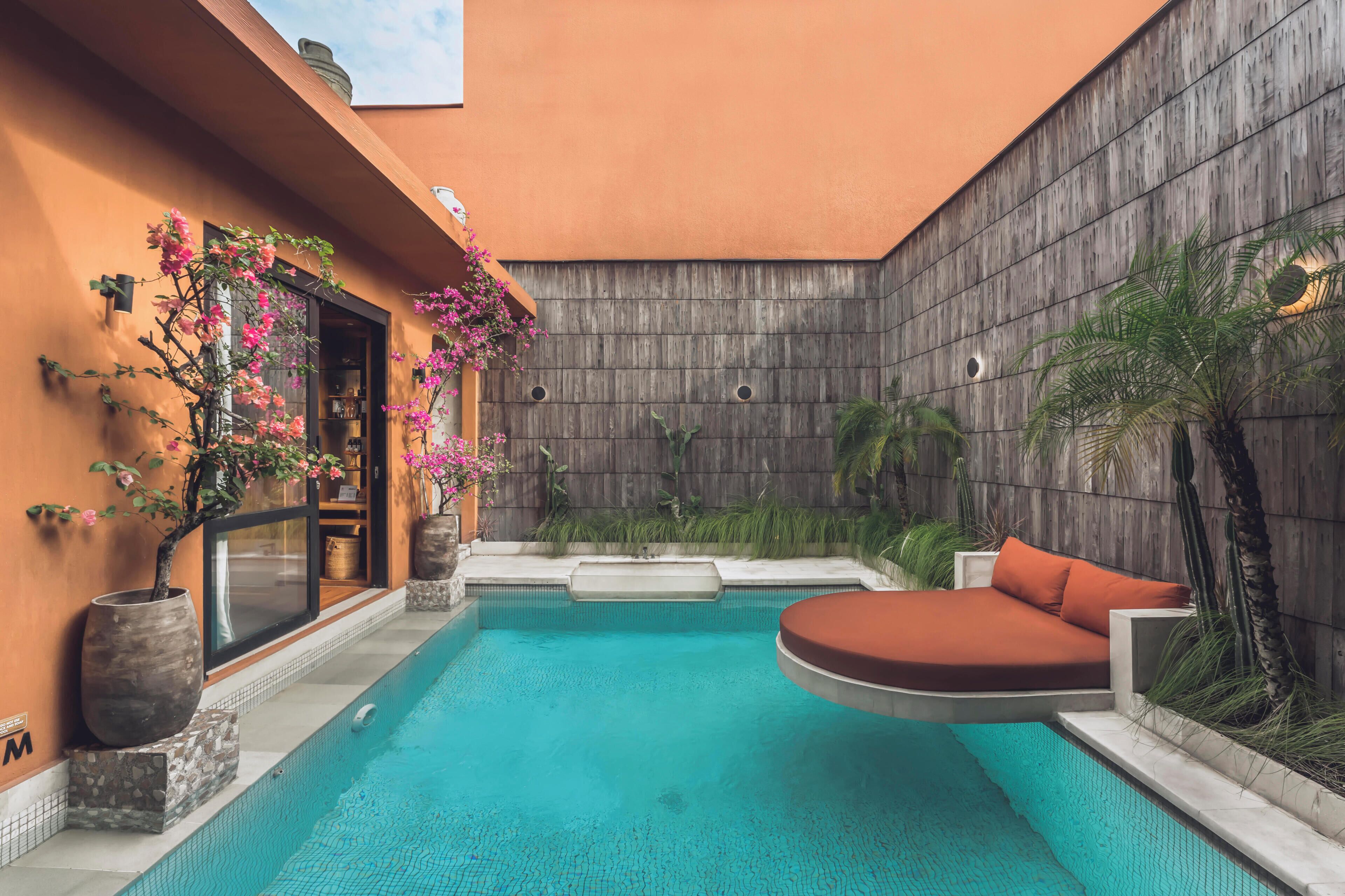 Piscina com deck de madeira, área de estar e vasos de plantas.