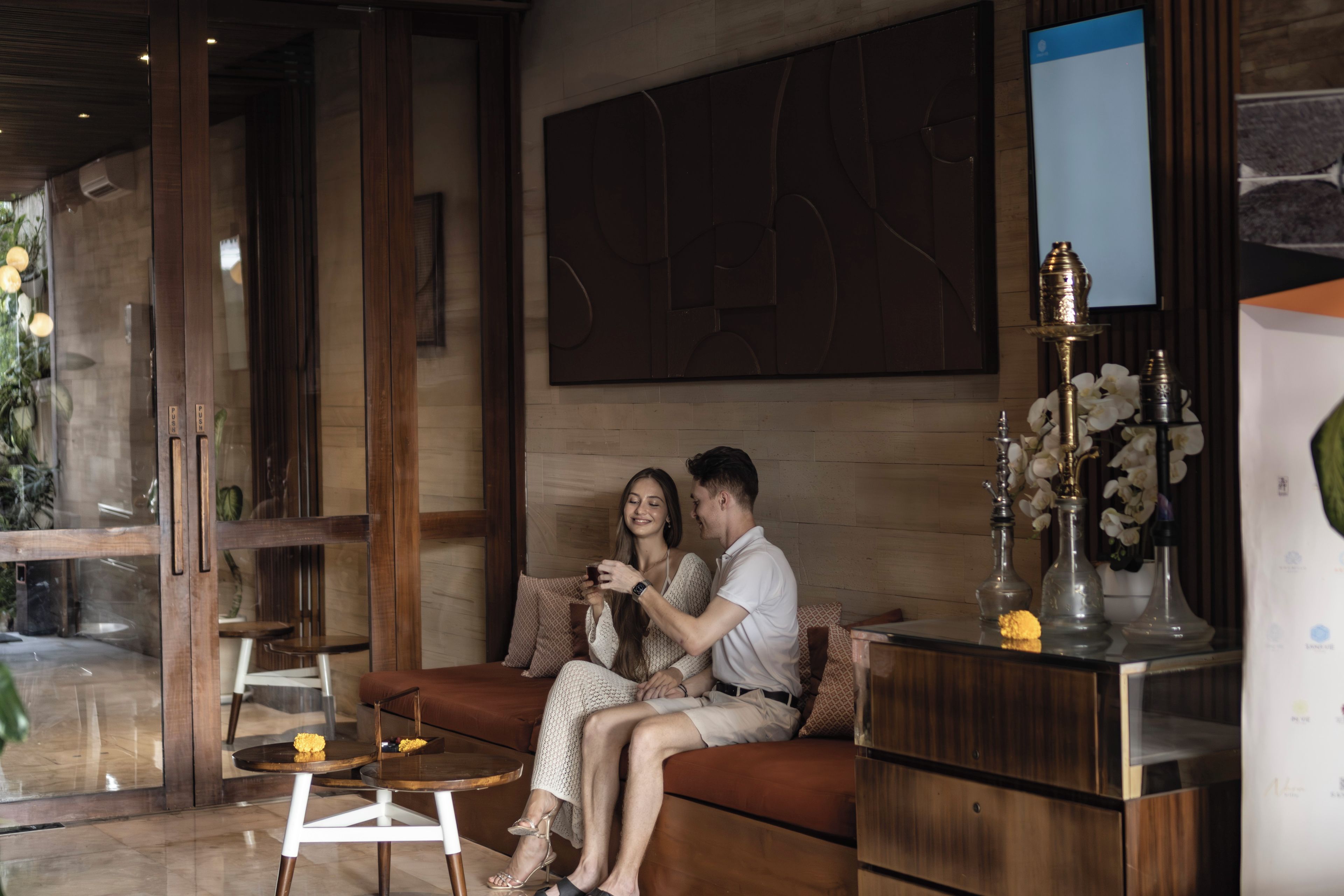 A modern interior with a wooden floor, a glass partition, a sofa, a coffee table, and decorative items.
