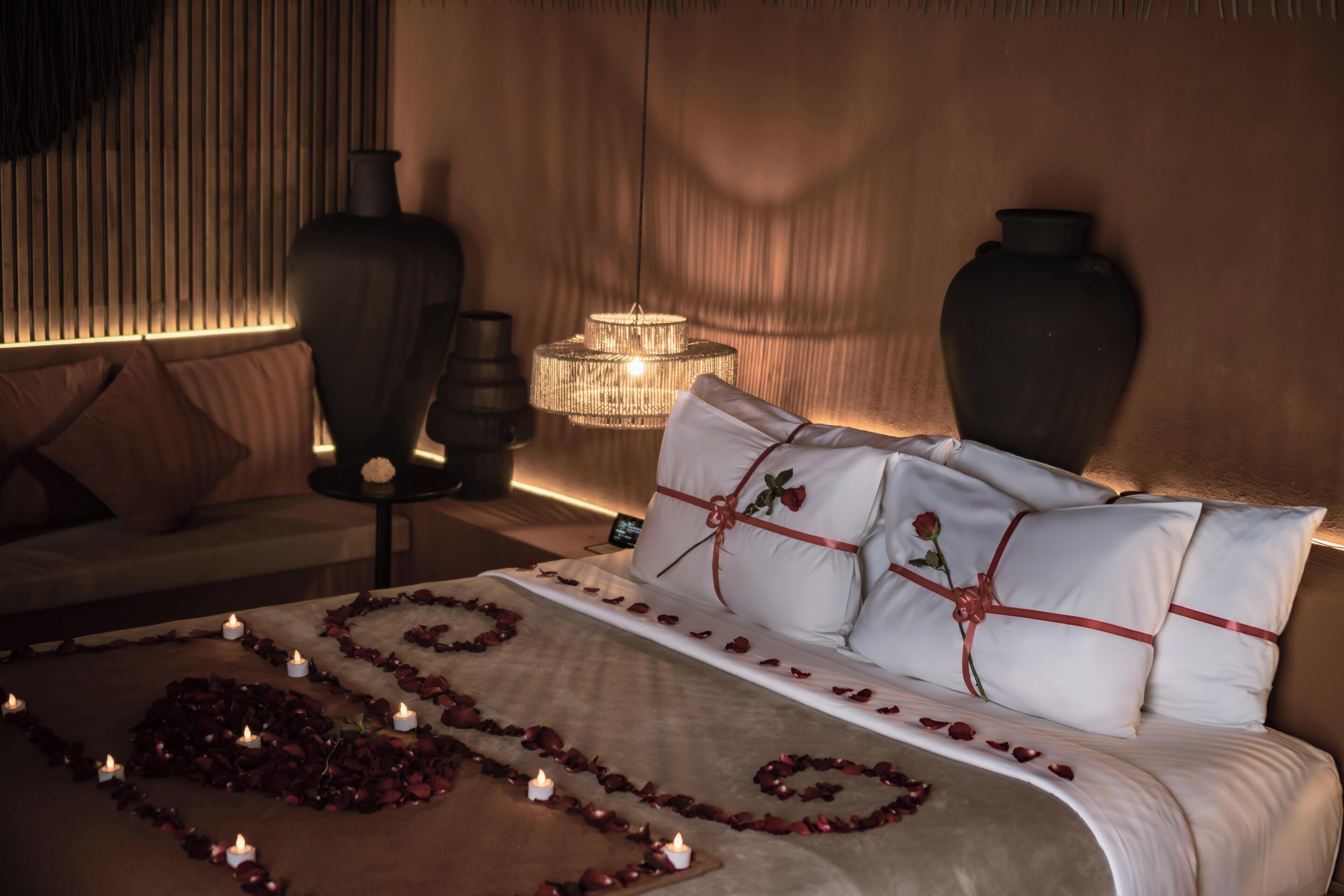 Un dormitorio con cama, mesitas de noche, una araña y jarrones decorativos.