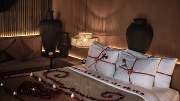 Un dormitorio con cama, mesitas de noche, una araña y jarrones decorativos.