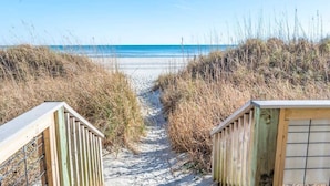 A sandy beach path leading to the ocean, flanked by wooden structures and tall grasses. - Beachfront condo w/ ocean views & hot tub (North Myrtle Beach)