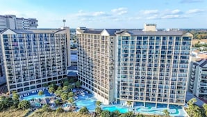 A hotel with multiple high-rise buildings, a central courtyard with a swimming pool, and a view of the surrounding landscape. - Beachfront condo w/ ocean views & hot tub (North Myrtle Beach)