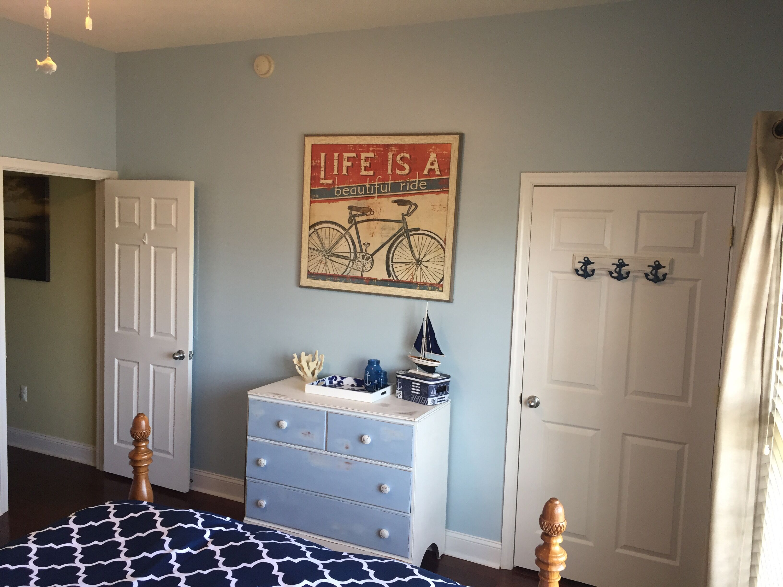 Een slaapkamer met een bed, een kaptafel en een bordje aan de muur.