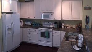 A kitchen with white cabinets, a microwave, a stove, and a sink. - Luxury Condo - Vofp - "Featured in Delaware Today" (Lewes)