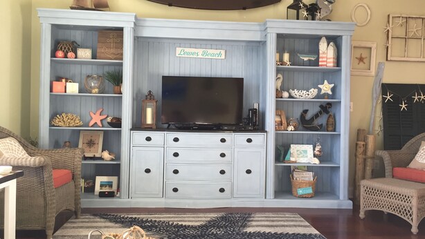 A living room with a television, wicker furniture, and nautical decor. - Luxury Condo - Vofp - "Featured in Delaware Today" (Lewes)