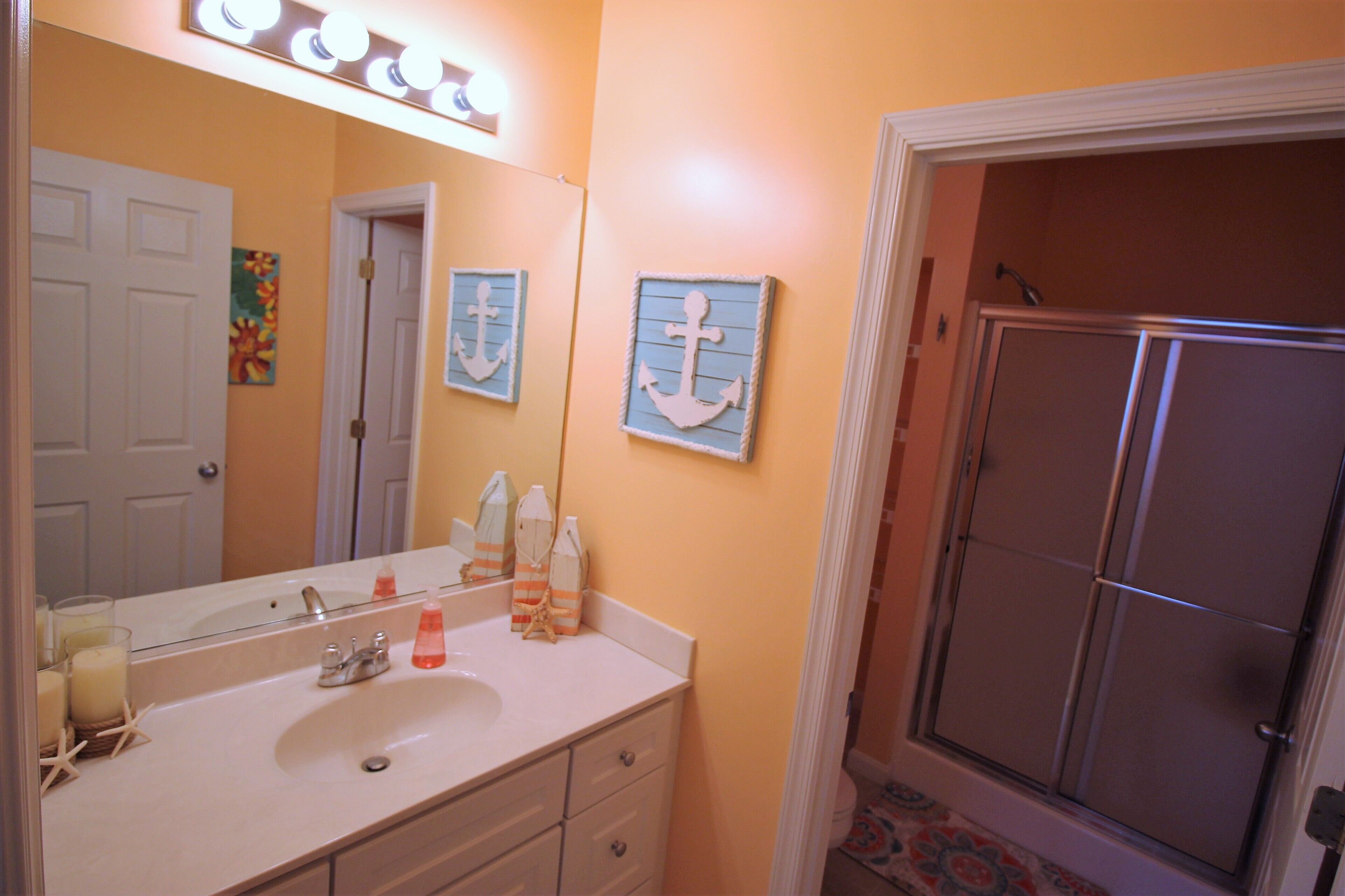 A bathroom with a sink, mirror, and shower.