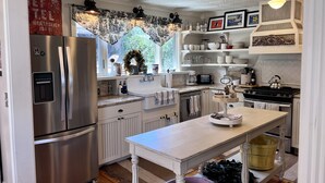 Una cocina con un refrigerador de acero inoxidable, un lavamanos, una estufa y una mesa de comedor.