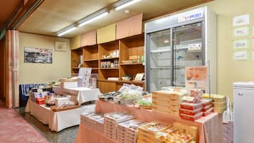 Una habitación con una mesa mostrando diferentes productos envasados, un refrigerador y estantes con artículos.