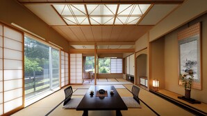 A traditional Japanese room with tatami flooring, a low table with tea set, sliding doors, and a view of greenery outside. - Bekkan Fujiya Ryokan (Kaminoyama)