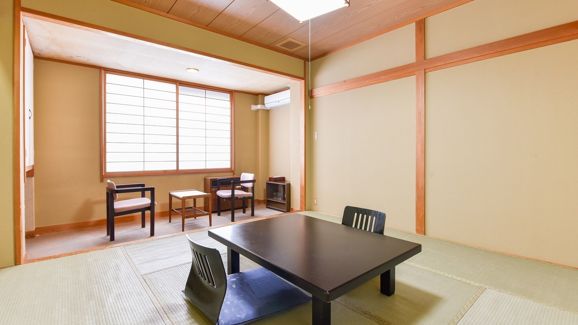 Um quarto japonês tradicional com tatames, uma mesa baixa e portas deslizantes.