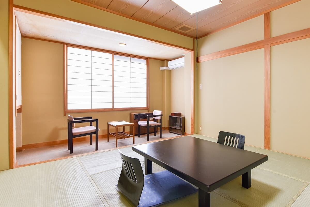 Ein traditioneller japanischer Raum mit Tatami-Böden, einem niedrigen Tisch und Schiebetüren.