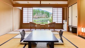 A traditional Japanese room with tatami flooring, a low table, two chairs, and a view of a mountain through shoji screens. - Bekkan Fujiya Ryokan (Kaminoyama)