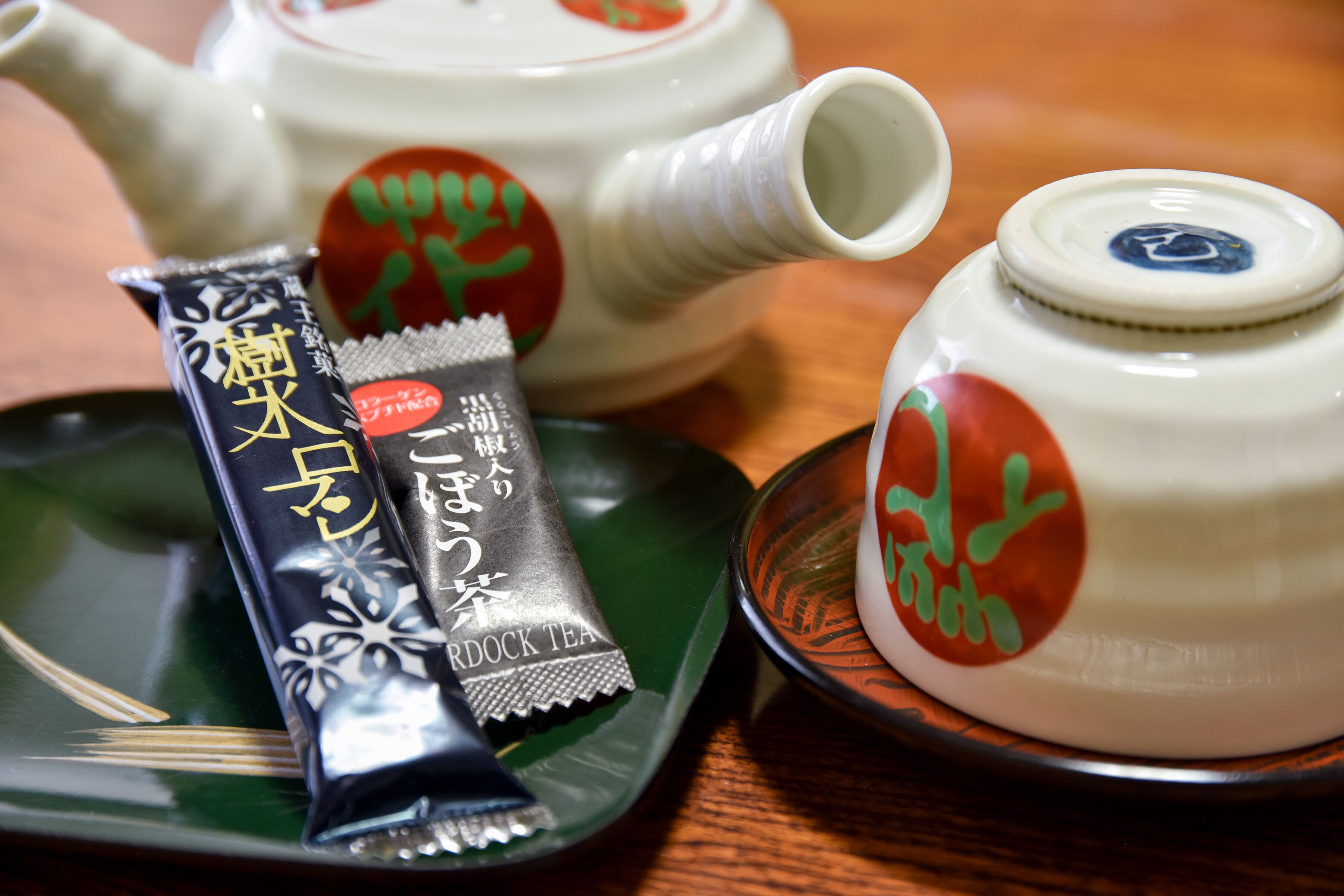 A teapot and a tea packet on a green tray.