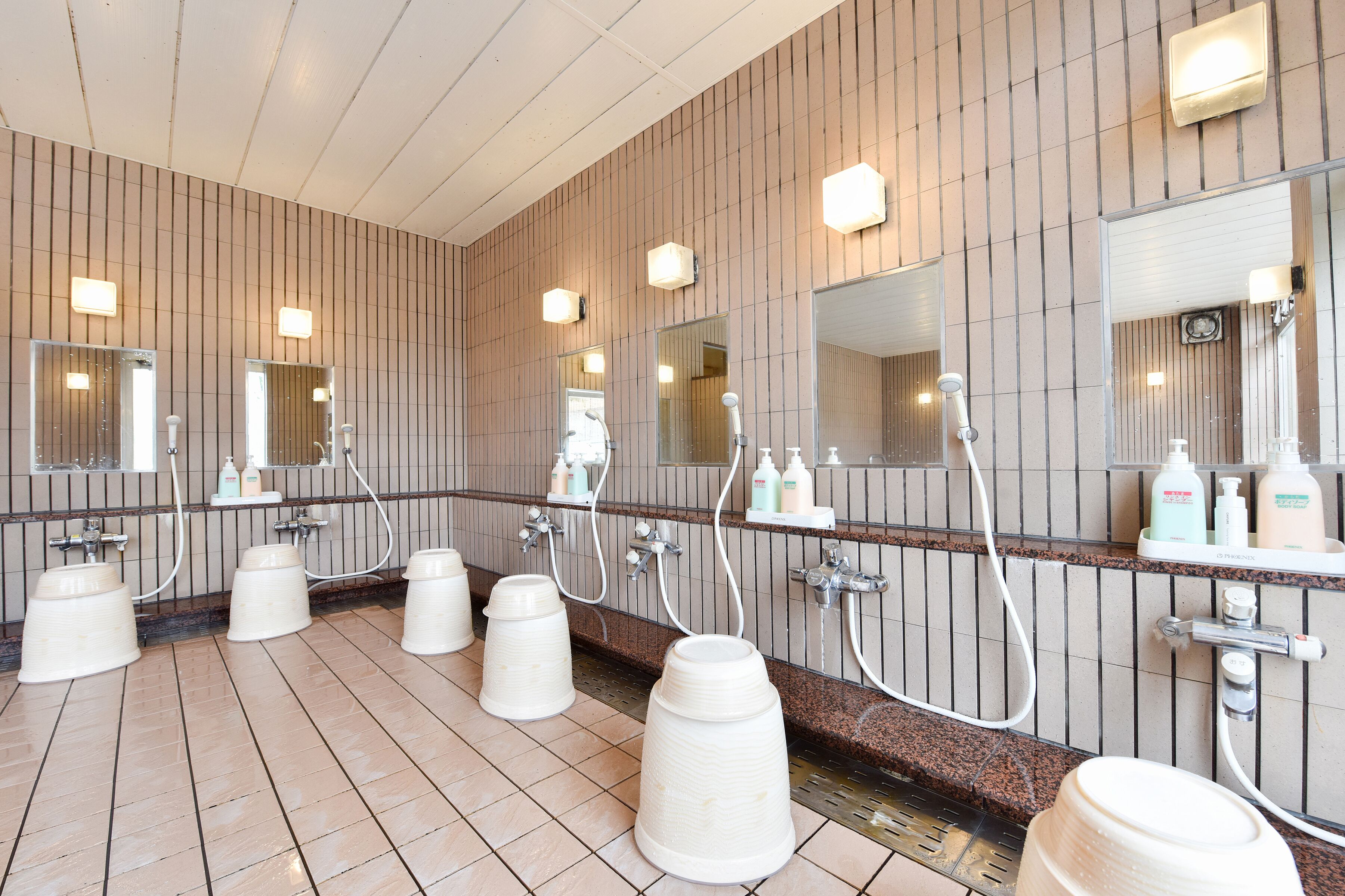 A modern bathroom with multiple sinks, mirrors, and hand dryers.