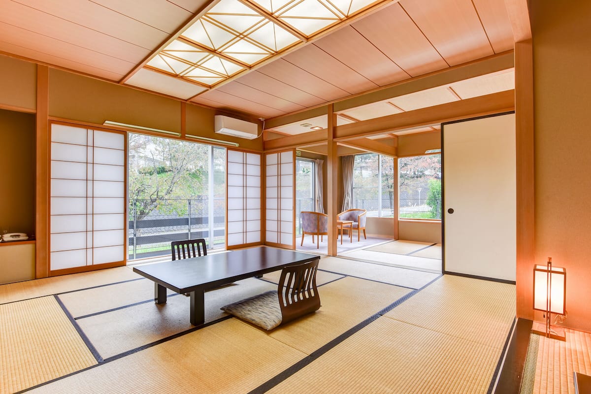 Ein traditioneller japanischer Raum mit Tatami-Böden, einem niedrigen Tisch und Schiebetüren.