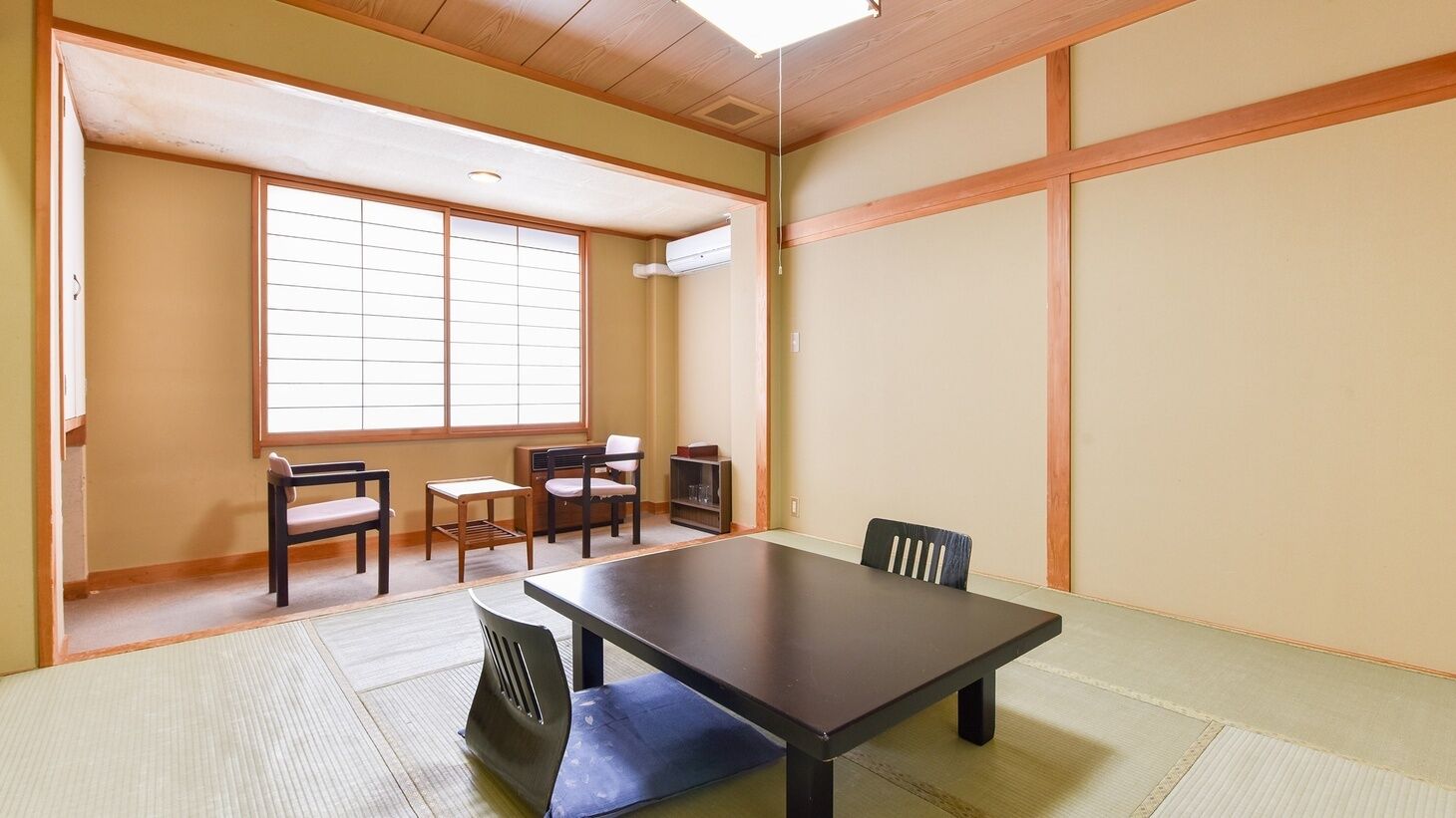 Una habitación japonesa tradicional con suelo de tatami, una mesa baja y puertas correderas.
