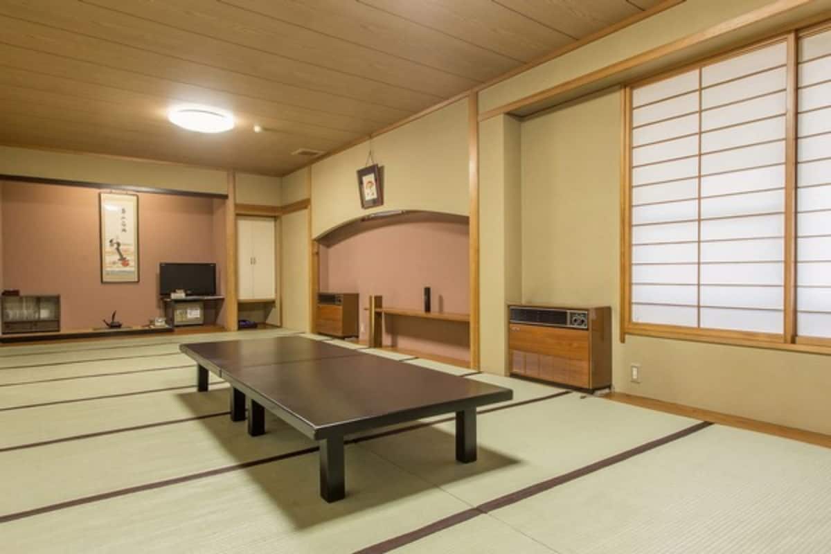 Ein Zimmer mit Tatami-Matten, einem Tatami-Tisch, einem Fernseher und einem Schrank.