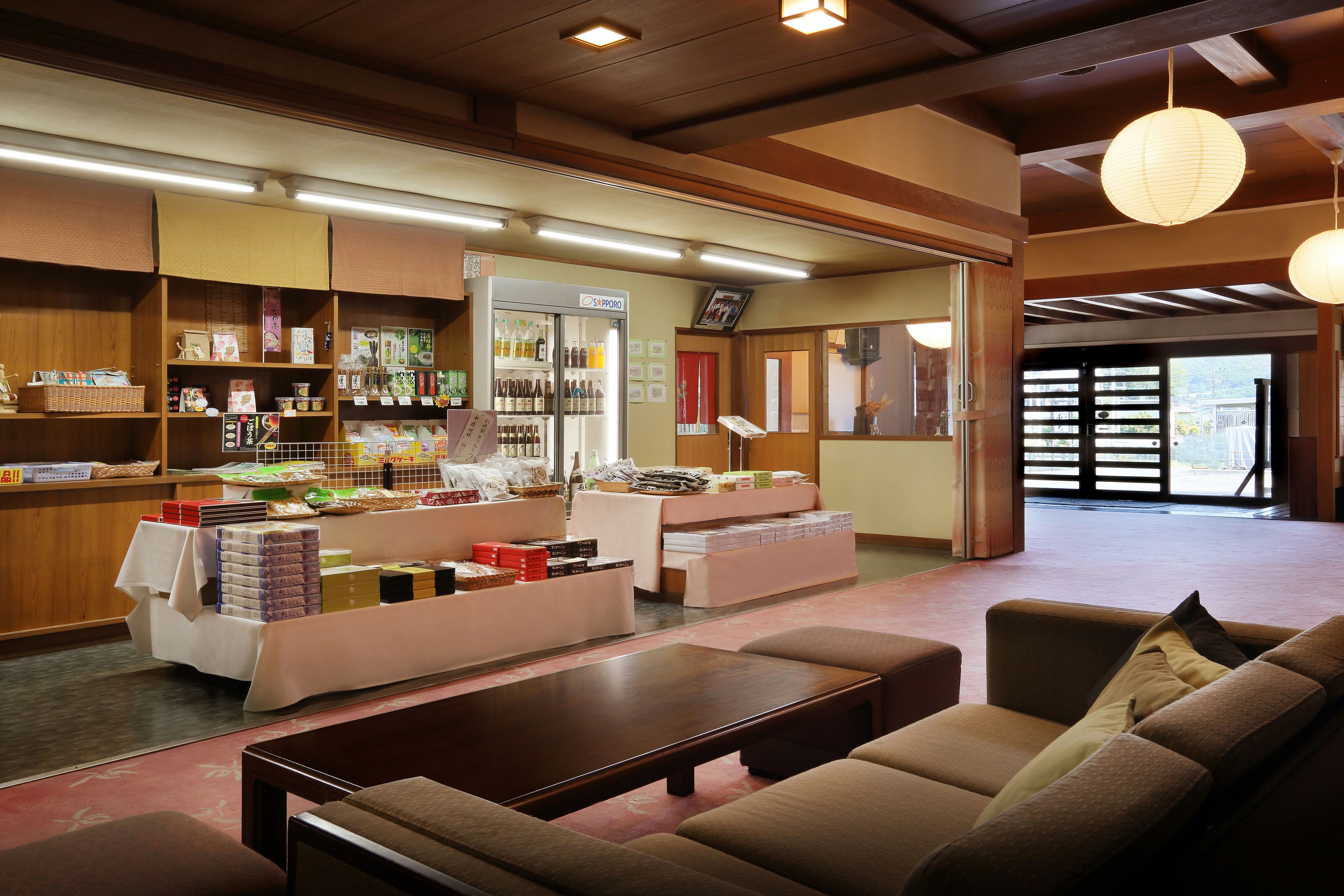 A cozy interior with a reception desk, seating area, and a refrigerator stocked with beverages.