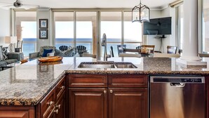 Una cocina moderna con una isla grande, lavavajillas y vista al océano.