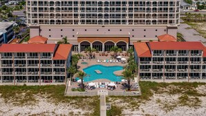 Un hotel con piscina central, varios balcones y ubicación frente a la playa.