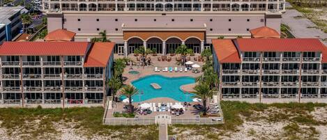 A hotel with a central pool, multiple balconies, and a beachside location.