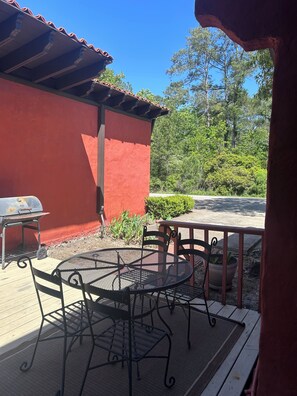 Une terrasse avec un barbecue, une table et des chaises d’extérieur, et un mur rouge.