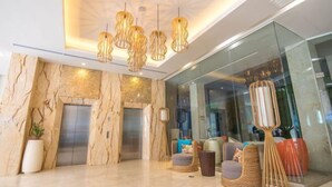 A modern lobby with marble walls, two elevators, and a seating area with wicker furniture. - Goldberry Lite Hotel (Ilo-Ilo City )