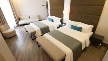 A hotel room with two beds, a sofa, a bench, and a nightstand.