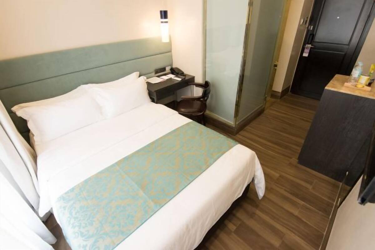A hotel room with a bed, a nightstand, a chair, and a desk.