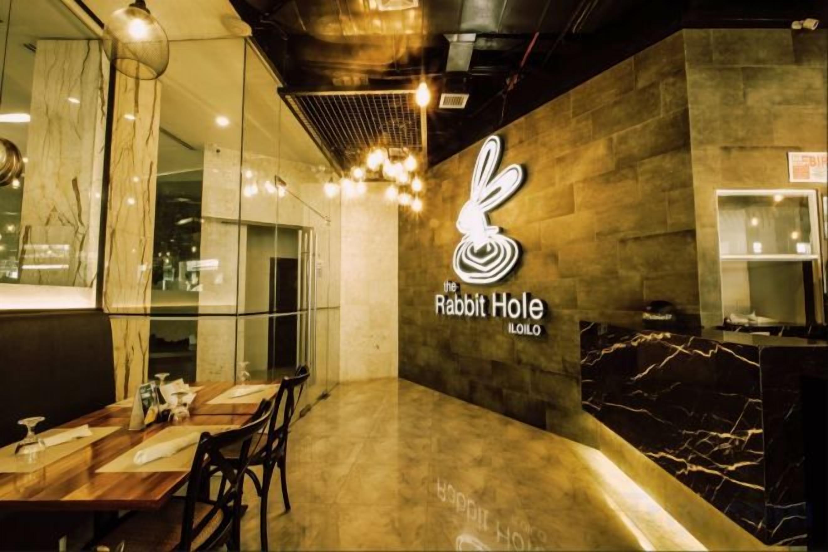 A restaurant interior with a marble countertop, a logo on the wall, and a seating area.