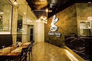 A restaurant interior with a marble countertop, a logo on the wall, and a seating area. - Goldberry Lite Hotel (Ilo-Ilo City )