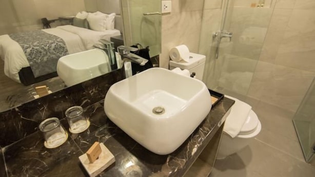 A modern bathroom with a large white sink, a glass shower enclosure, and a visible toilet. - Goldberry Lite Hotel (Ilo-Ilo City )