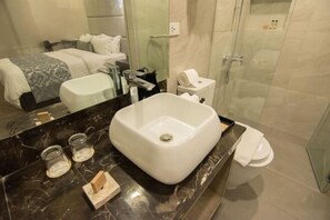A modern bathroom with a large white sink, a toilet, and a glass shower enclosure. - Goldberry Lite Hotel (Ilo-Ilo City )