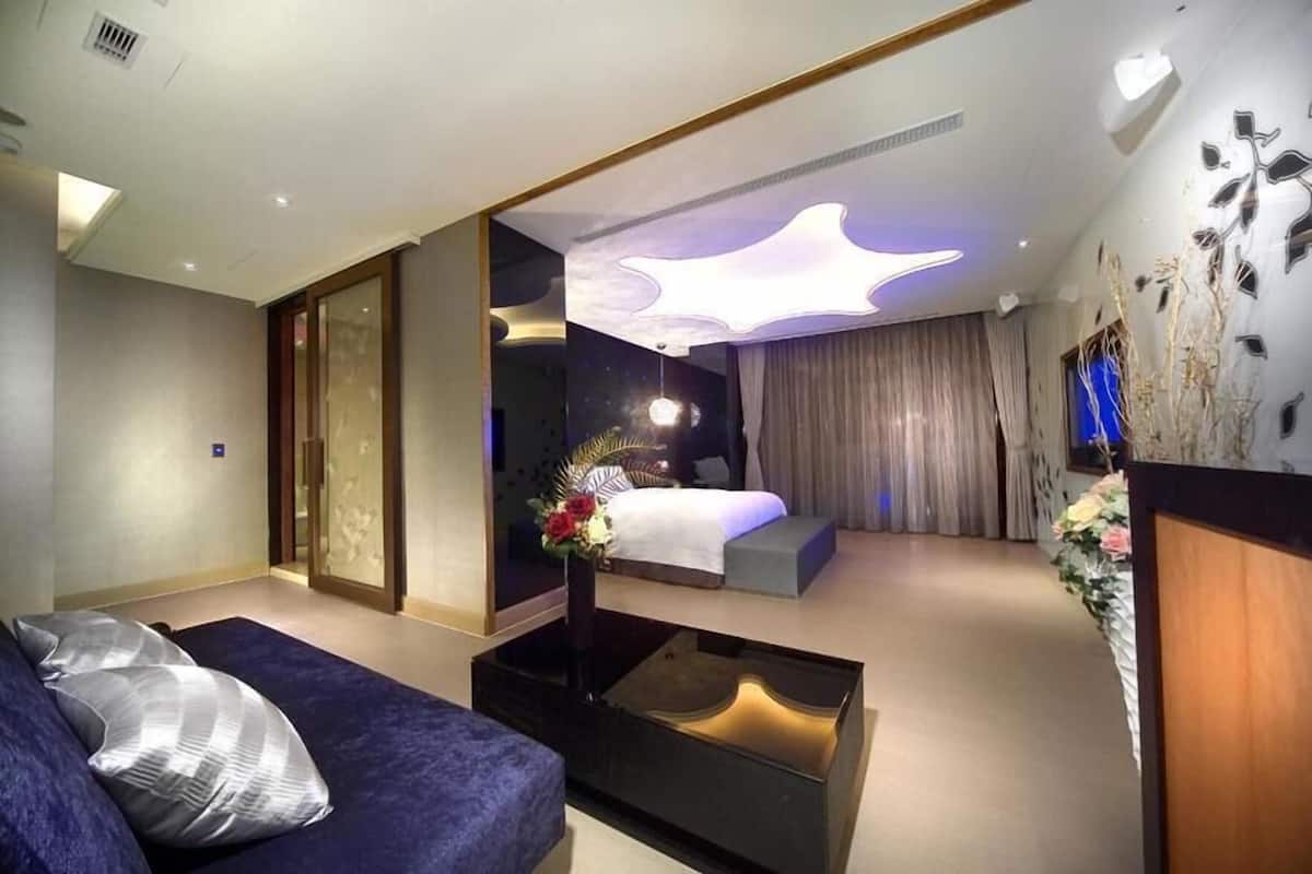 A modern hotel room with a bed, sofa, and a coffee table.